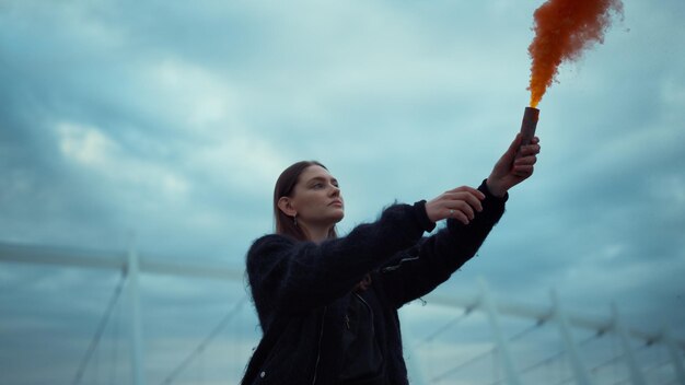 Girl holding smoke bomb in hand focused woman waving hand with smoke grenade