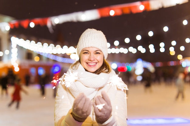 Girl holding a sparkler in her hand outdoor winter city background snow snowflakes