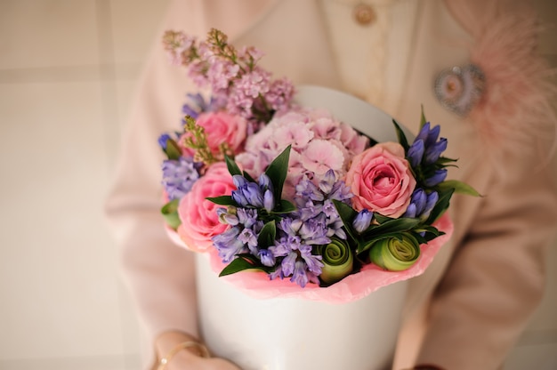 Ragazza che tiene una scatola di primavera di teneri fiori rosa e viola