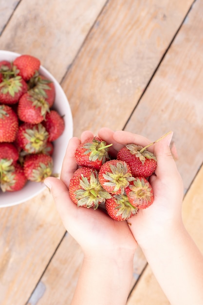 Girl holding strawberries in hands