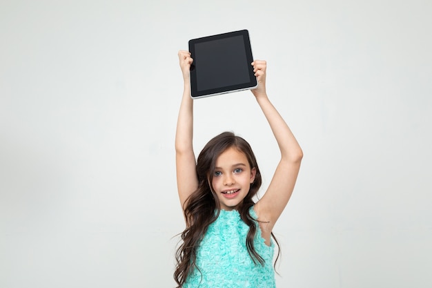 Girl holding a tablet with a blank screen over her head to insert a web page or advertisement on a white background.