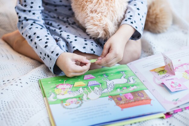 Girl holding a teddy bear on the bed at Christmas