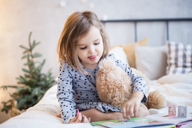 クリスマスにベッドでテディベアを保持している女の子