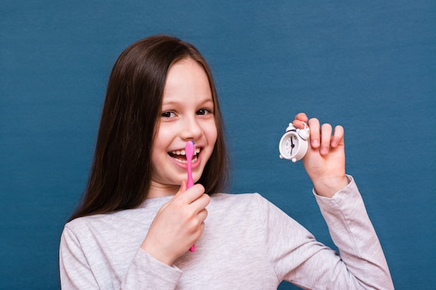 Girl holding a toothbrush and an alarm clock