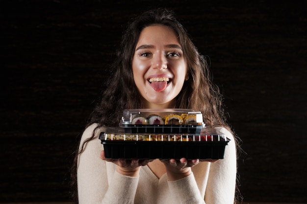 Girl holding two sushi boxes on black background