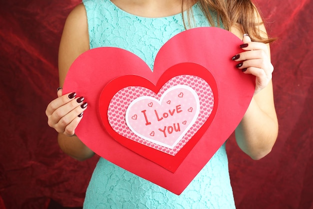 Girl holding Valentine card on red background