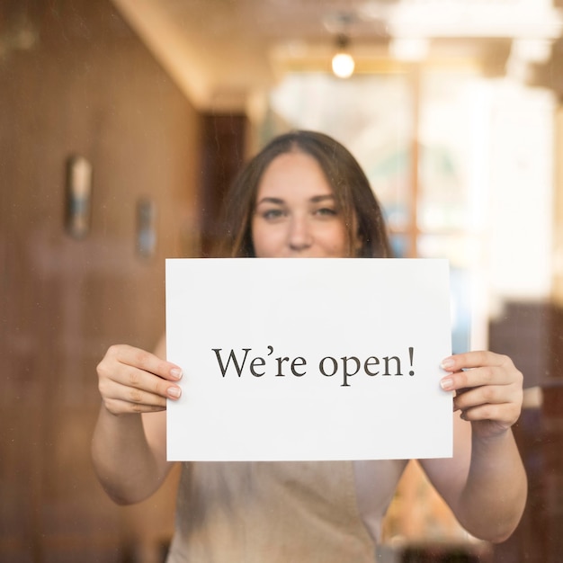 Girl holding a we're open sign after the end of quarantine