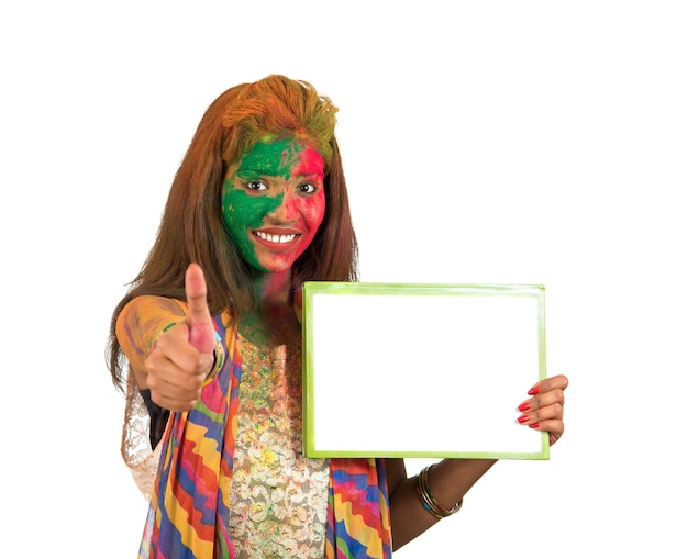 Girl holding a white signboard with face painted with color in Festival of Colour Holi