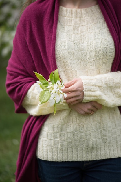 The girl holds apple blossoms in her hand