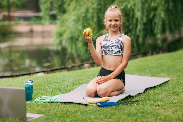 A girl holds an apple in her hand after undergoing an online outdoor training