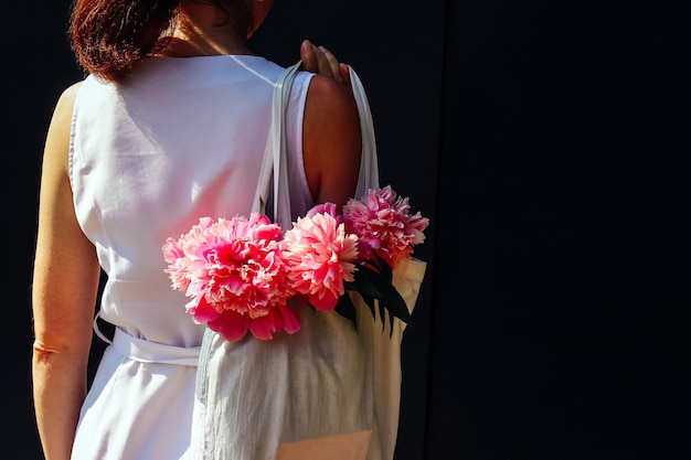 The girl holds a bag with summer flowers peonies summer mood lifestyle