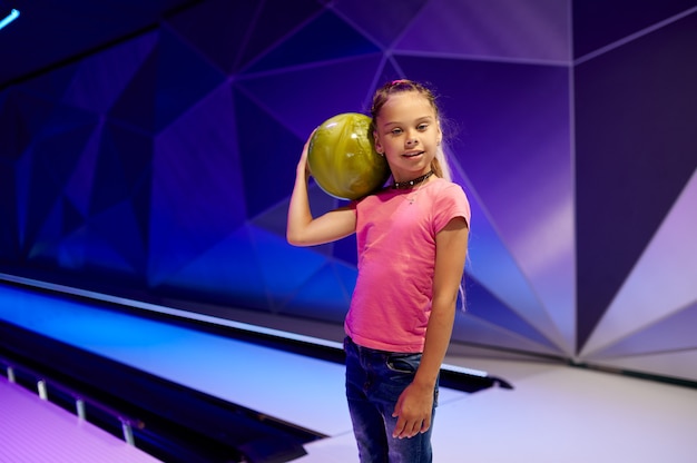 Girl holds a ball at the lane in bowling alley