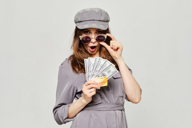 Girl holds a bank credit card and us dollars as a concept of loans.