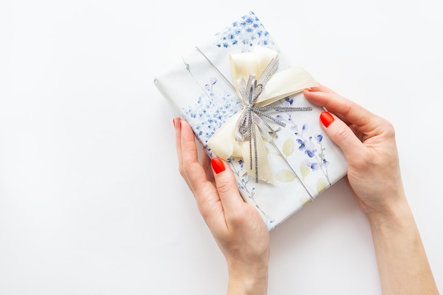 The girl holds a beautifully wrapped gift in her hands on a white background Time to wrap presents Surprise Christmas and New Year concept