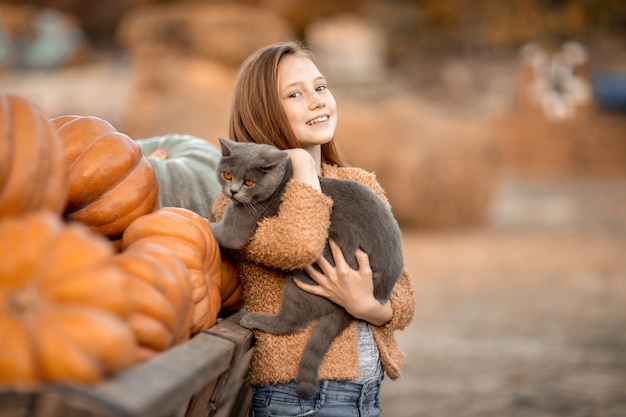 A girl holds a black cat in her arms.