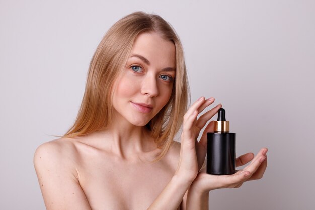 Girl holds a black shirt with serum cosmetics