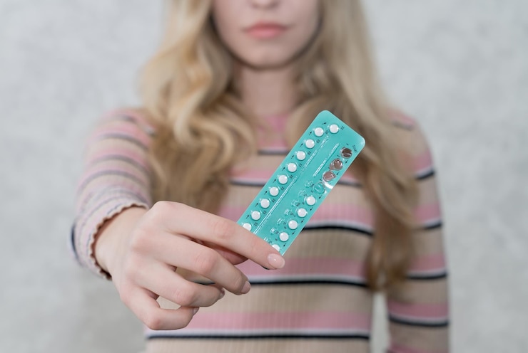Photo girl holds a blister with oral contraceptives in her hand