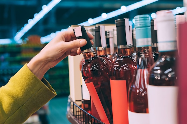 A girl holds a bottle of wine in the store.