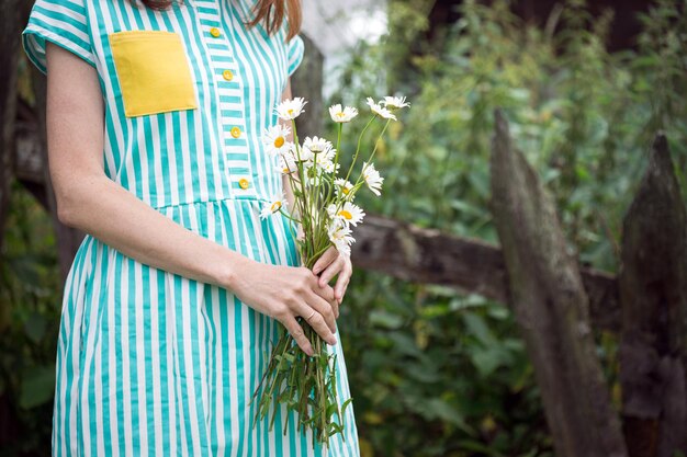 girl holds bouquet of camomile in hands