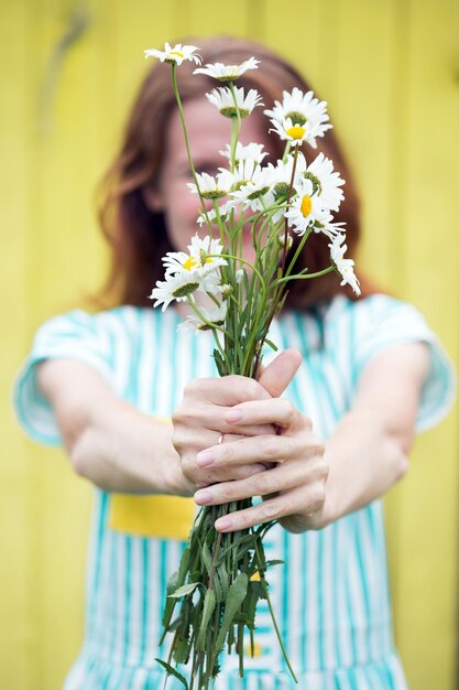 Girl holds bouquet of camomile in hands