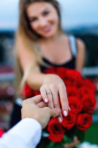 The girl holds a bouquet of flowers and gives the guy a hand on her ring finger a golden ring