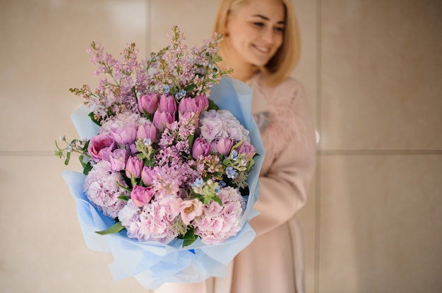 Girl holds bouquet of peonies, roses and lilac