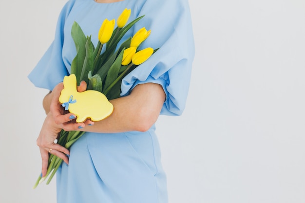 Girl holds a bouquet of tulips and ginger cookies