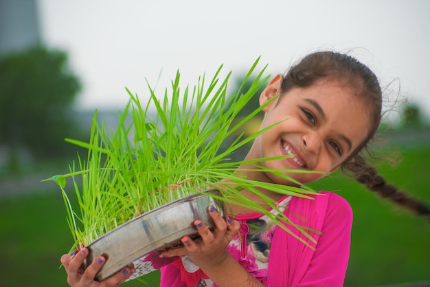 A girl holds a bowl of grass in her hands