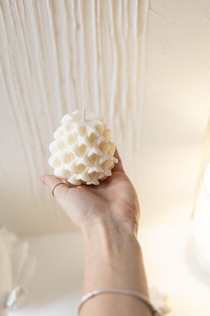 A girl holds a candle of white wax on her hand