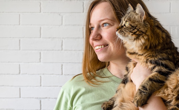 Foto la ragazza tiene il gatto tra le braccia piccolo concetto di famiglia