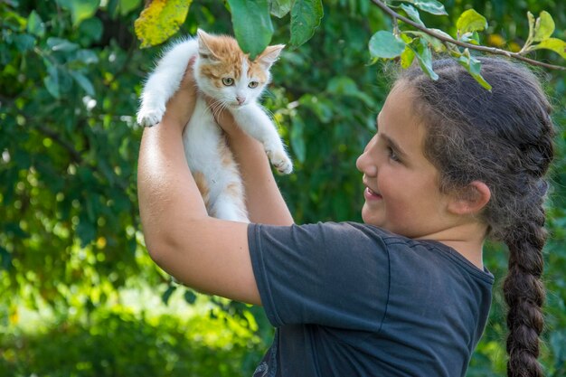 A girl holds a cat in her arms.