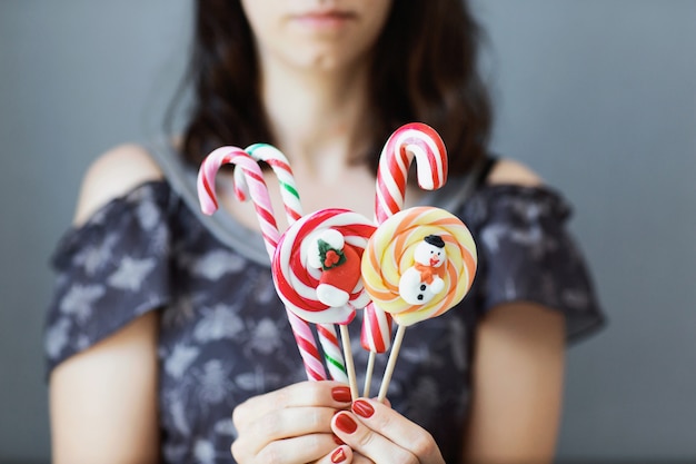 The girl holds colored Christmas candies in her hands. 