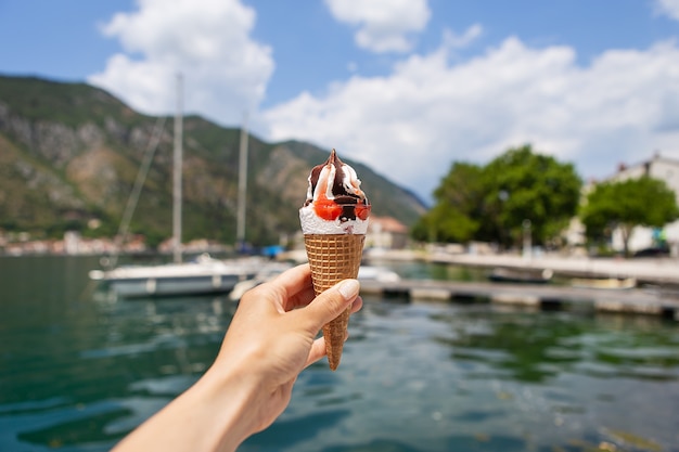 girl holds colorful ice cream on the background of the Bay of Kotor