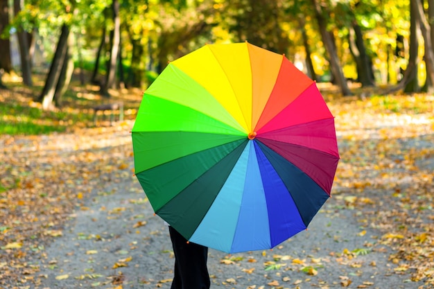 A girl holds a colorful umbrella while walking in the park