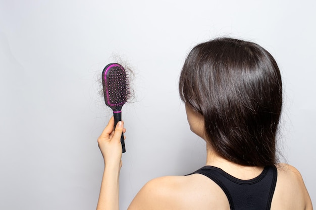 The girl holds a comb for hair with fallen hair