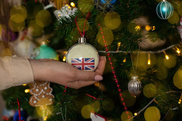 A girl holds a decoration on a Christmas tree with the flag of Great Britain