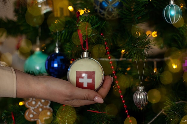 A girl holds a decoration on a Christmas tree with the flag of Switzerland