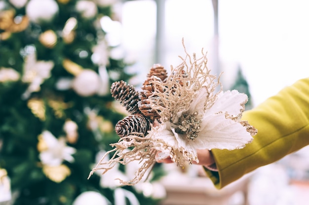 The girl holds decorative flowers in her hands. Against the background of the counter in the store