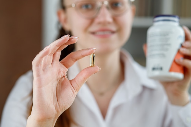 Photo the girl holds a fish oil capsule in her hand omega3 capsules in the doctors hand