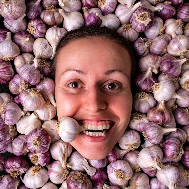 The girl holds a garlic bulb in her teeth Portrait of a woman among many garlic bulbs