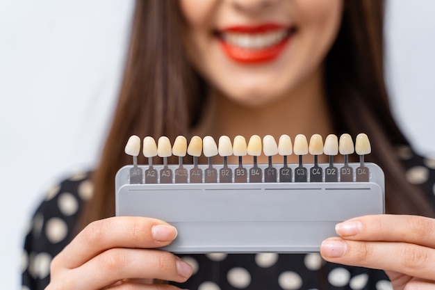 Girl holds in hands pallete for teeth color select. Blurred background. Selective focus.