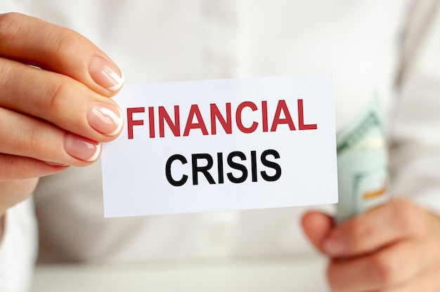 Photo the girl holds in her hand a hundred dollar bill and a sign that says financial crisis the concept of finance and economics