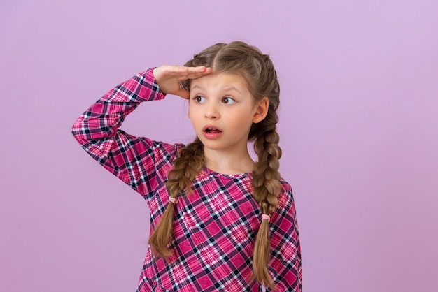 The girl holds her hand near her forehead and looks into the distance.