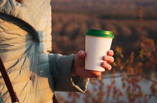 The girl holds in her hand a paper cup for coffee. Free space for text