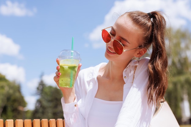 The girl holds in her hand a summer refreshing cocktail in the city