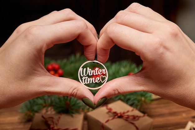 The girl holds in her hands the inscription winter time on the background of Christmas accessories