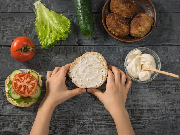 La ragazza tiene tra le mani l'altra metà del panino hamburger.