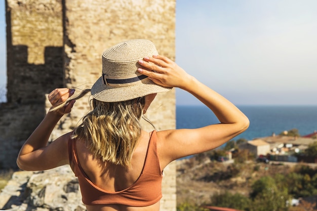 소녀는 바다 여행에 그녀의 여름 밀 짚 모자를 보유하고있다.