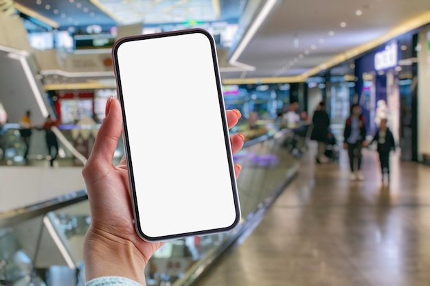 사진 소녀 는 슈퍼마켓 의 배경 에  ⁇  화면 을 가진 스마트폰 의 모형 을 손 에 들고 있다