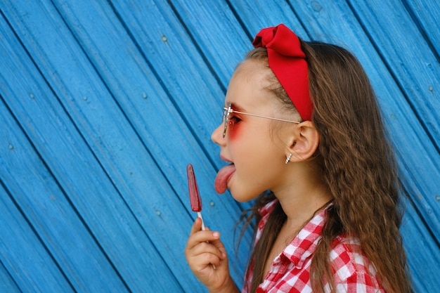 A girl holds a lollipop in her hands licking it with her tongue